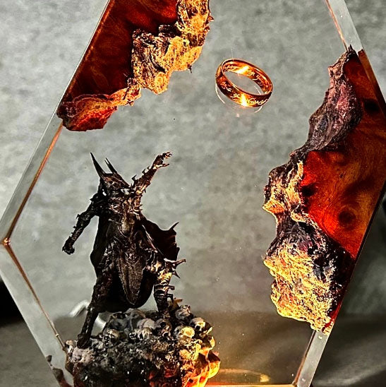 Custom fantasy diorama: transparent hexagon encasing levitating gold ring, volcanic terrain, and ominous warrior statuette on lit wooden base