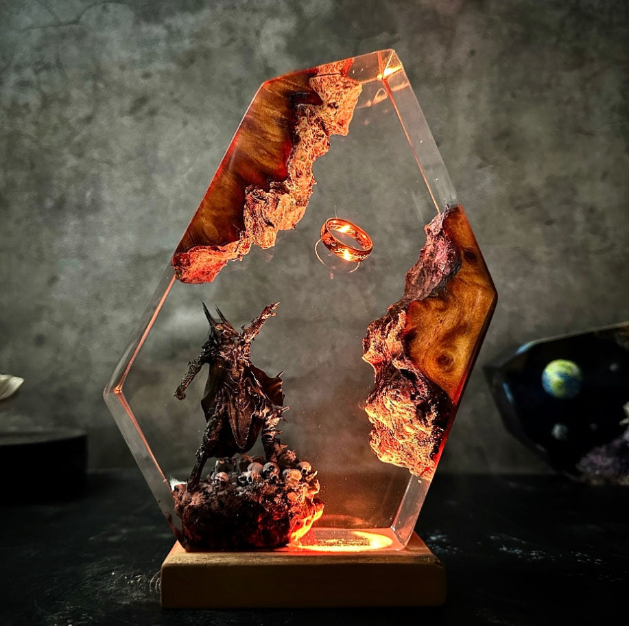 Hexagonal resin art diorama featuring dark fantasy scene with glowing ring, lava-like elements, and menacing warrior figure on illuminated wooden base