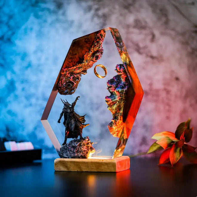 Artisan resin creation: glowing geometric display featuring suspended ring, fiery landscape, and dark sentinel figure on illuminated stand